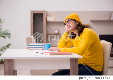 Young male student preparing for exams at home 76043751