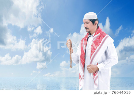 Asian Muslim man praying with prayer beads on his hands 76044019