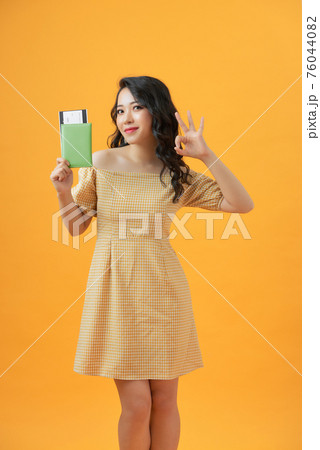 Beautiful portrait young asian woman smiling gesture ok over yellow background, holding passport. Beautiful portrait young asian woman smiling gesture ok over yellow background, holding passport. 76044082