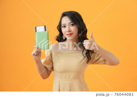 Woman over isolated yellow background in vacation holding a passport and plane with thumb up Woman over isolated yellow background in vacation holding a passport and plane with thumb up 76044083