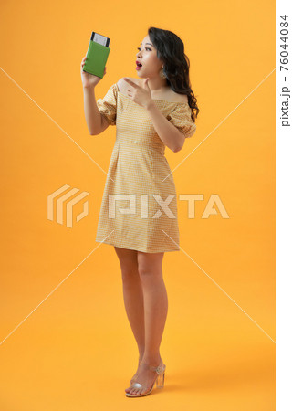 Tourist woman on vacation holding passport very happy pointing with hand and finger 76044084