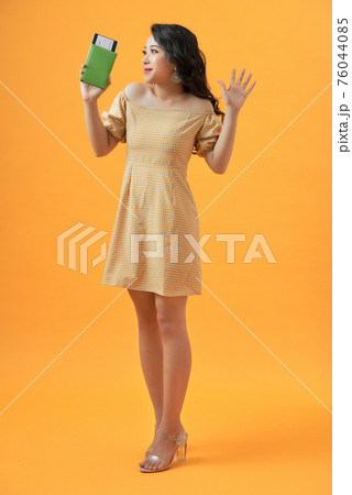 Young smiling excited woman student holding passport boarding pass ticket isolated on yellow background Young smiling excited woman student holding passport boarding pass ticket isolated on yellow background 76044085