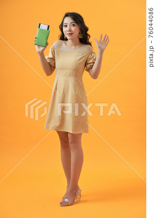 Portrait of a cheerful cute asian girl traveller showing passport with tickets isolated over yellow background Portrait of a cheerful cute asian girl traveller showing passport with tickets isolated over yellow background 76044086