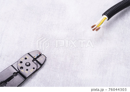Wire stripper pliers and exposed electrical cable on the electrician's desk Wire stripper pliers and exposed electrical cable on the electrician's desk 76044303