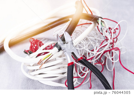 Electric cable cutters and a lot of wires on the electrician's desk Electric cable cutters and a lot of wires on the electrician's desk 76044305