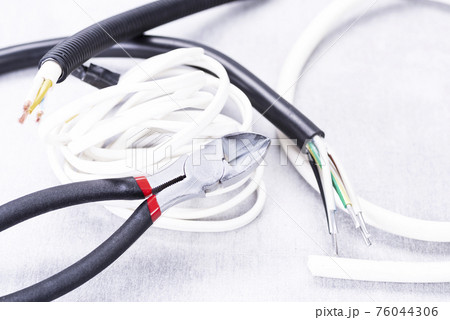 Electric cable cutters and a lot of wires on the electrician's desk 76044306