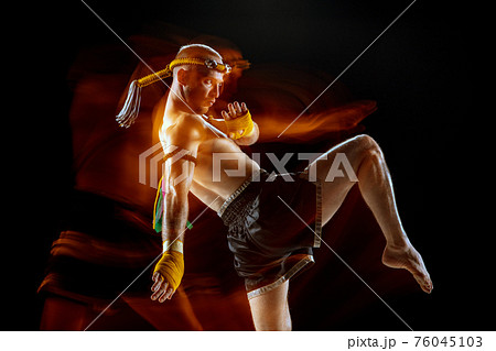 Young man thai boxer training over dark background in neon mixed light. Young man thai boxer training over dark background in neon mixed light. 76045103