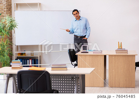 Young male teacher in the classroom 76045485