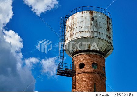 Water tower made of brick and metal with round windows Water tower made of brick and metal with round windows 76045795