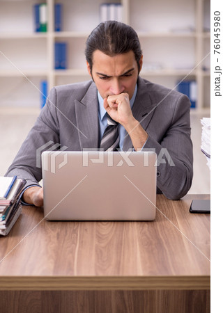 Young male employee unhappy with excessive work in the office Young male employee unhappy with excessive work in the office 76045980