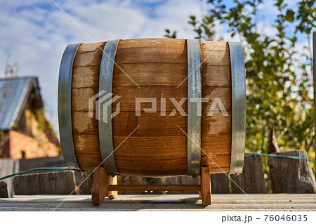 Oak barrel for storage wine lies on special support in yard 76046035