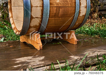 Oak barrel for storage wine lies on special support in yard 76046076