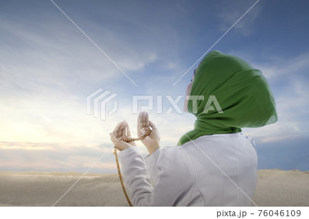 Asian Muslim woman in veil praying with prayer beads on her hands Asian Muslim woman in veil praying with prayer beads on her hands 76046109
