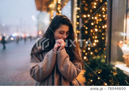 Woman by illuminated showcase on city street. 76046600