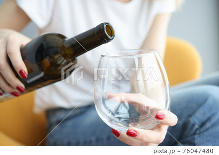 Woman hand pours wine into large glass Woman hand pours wine into large glass 76047480