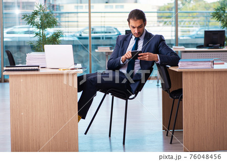Young male bookkeeper working in the office Young male bookkeeper working in the office 76048456