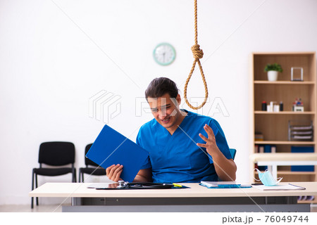 Young male doctor committing suicide at workplace 76049744