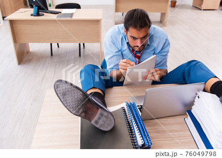 Young male employee unhappy with excessive work in the office Young male employee unhappy with excessive work in the office 76049798