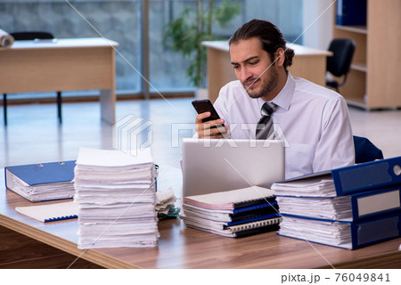 Young male employee unhappy with excessive work in the office Young male employee unhappy with excessive work in the office 76049841