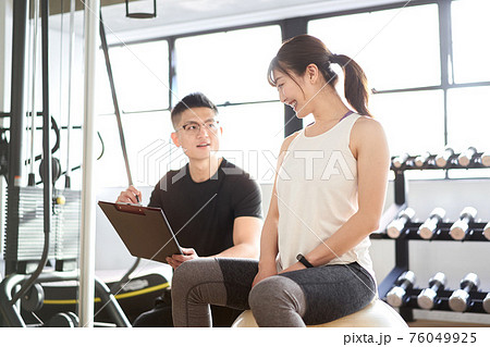 アジア人女性に指導をする男性パーソナルトレーナー アジア人女性に指導をする男性パーソナルトレーナー 76049925