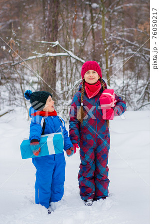 Happy children in a winter snow-covered forest with gift boxes. Happy children in a winter snow-covered forest with gift boxes. 76050217