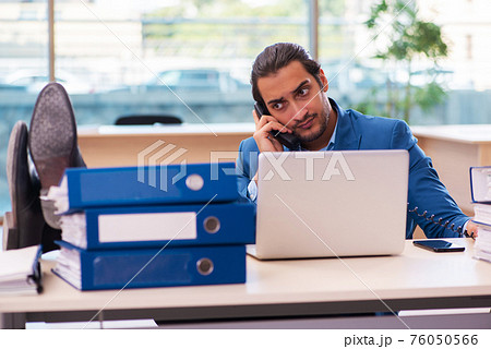 Young male employee and too much work in the office 76050566