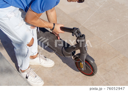 Young man folding electric scooter close up 76052947