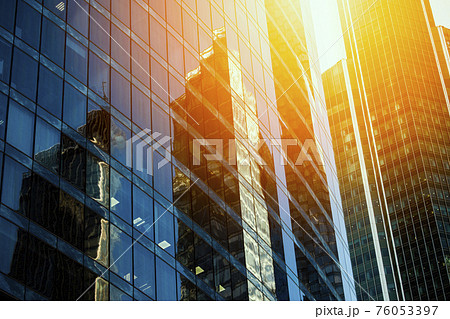 Skyscraper glass facades on a bright sunny day with sunbeams in the blue sky. Modern buildings in Moscow business district La Defense. Bottom up view Skyscraper glass facades on a bright sunny day with sunbeams in the blue sky. Modern buildings in Moscow business district La Defense. Bottom up view 76053397