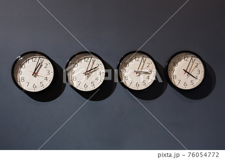 Four clocks on the black wall 76054772
