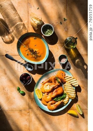Mediterranean lunch at sand table: seafood shrimps, pumpkin soup, seeds 76055759