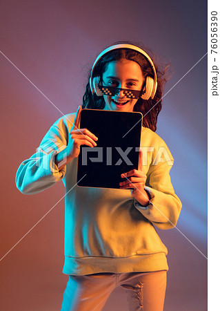 Young beautiful girl in headphones isolated on light background in neon light 76056390
