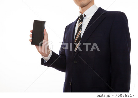 右手に持ったスマートフォンの画面を見せるスーツ姿の男性 横向きの写真素材