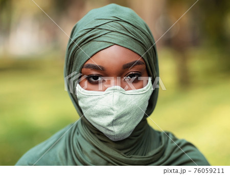 African Muslim Woman Wearing Protective Face Mask And Hijab Outdoors 76059211