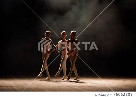 A group of small ballet dancers rehearses on stage with light and smoke. 76062808