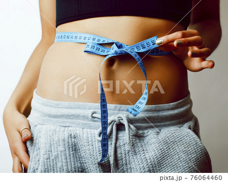 woman measuring waist with tape on knot like a gift close up abc isolated 76064460