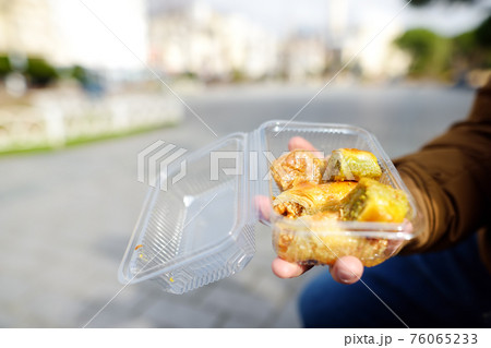 A male tourist bought a baklava and is going to try it. Traditional turkish dessert Baklava. Ramadan dessert. A male tourist bought a baklava and is going to try it. Traditional turkish dessert Baklava. Ramadan dessert. 76065233