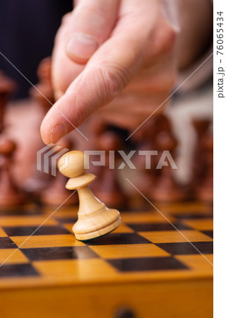 Old male employee playing chess at workplace 76065434