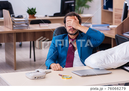 Young male employee coming to work straight from bed Young male employee coming to work straight from bed 76066279