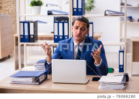 Young handsome employee sitting in the office Young handsome employee sitting in the office 76066280