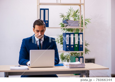 Young male employee working in the office 76066344
