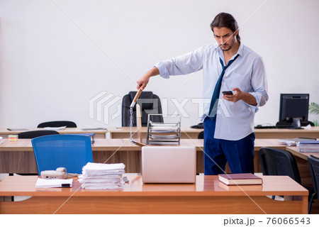 Young male furious employee holding nun-chucks in the office 76066543
