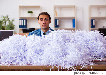 Young male employee and a lot of cut papers in the office 76066657