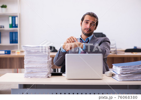 Young male employee unhappy with excessive work in the office 76068380