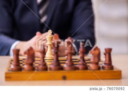 Young male employee playing chess at workplace Young male employee playing chess at workplace 76070092
