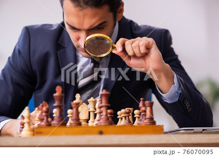 Young male employee playing chess at workplace 76070095