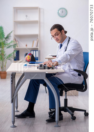 Young male doctor cardiologist working in the clinic Young male doctor cardiologist working in the clinic 76070733