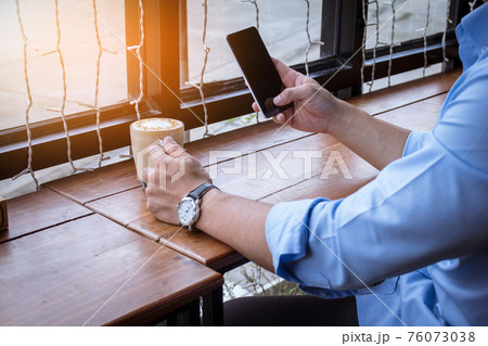 Close up of men hands holding touching mobile phone with blank copy space for your text message on wood 76073038