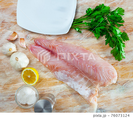 Raw perch fish fillet with parsley and lemon 76073124