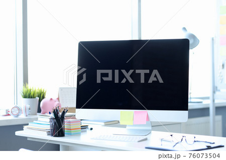 Computer with multicolored stickers standing on desktop in office Computer with multicolored stickers standing on desktop in office 76073504