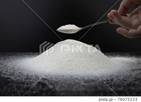 Spoon in sugar on a black background. The concept of addiction to sweets. Macro photo of granulated sugar. Spoon in sugar on a black background. The concept of addiction to sweets. Macro photo of granulated sugar. 76075223